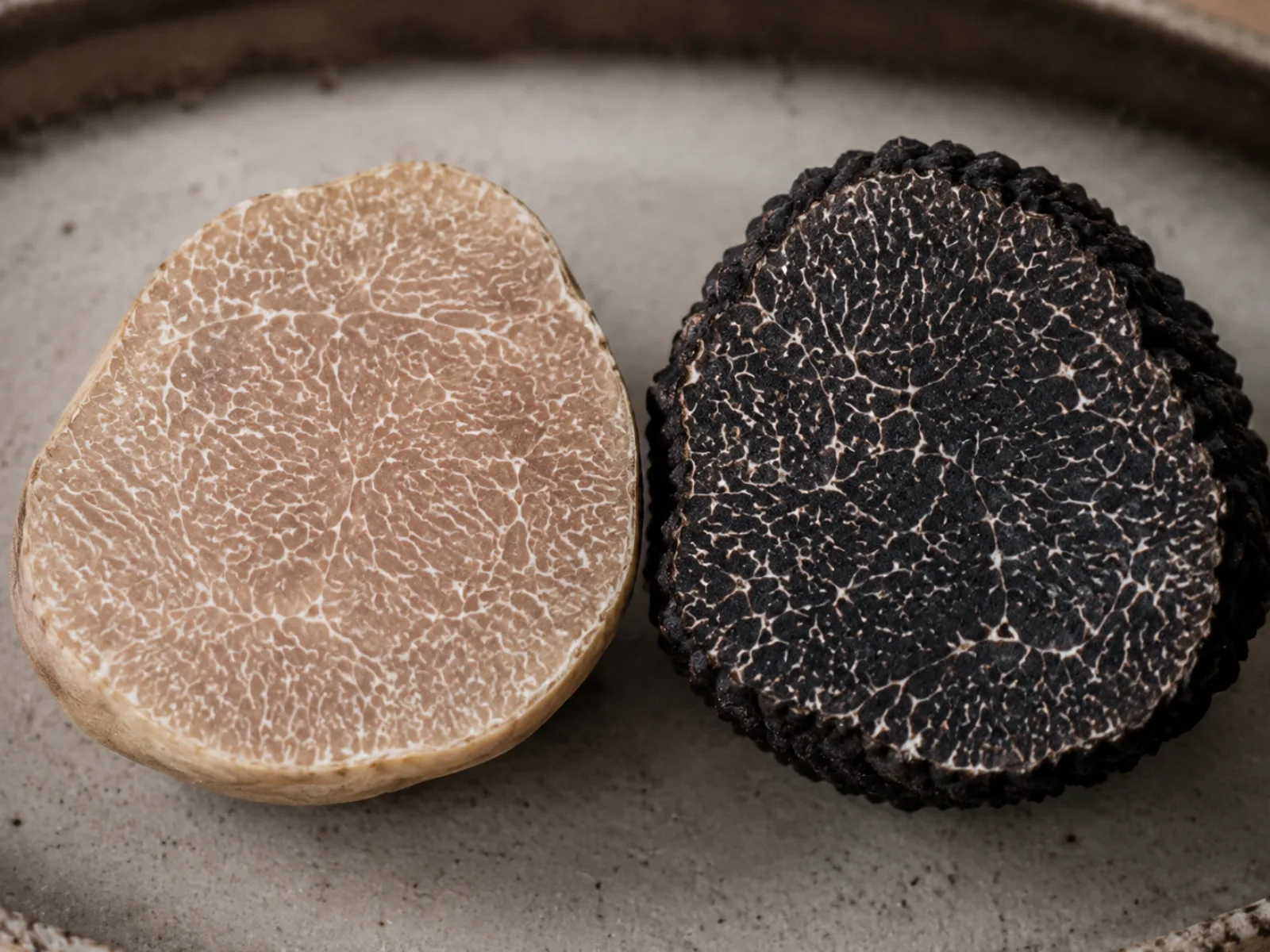 Sezioni dei due tartufi a confronto: polpa chiara con venature fitte e polpa nero-violacea