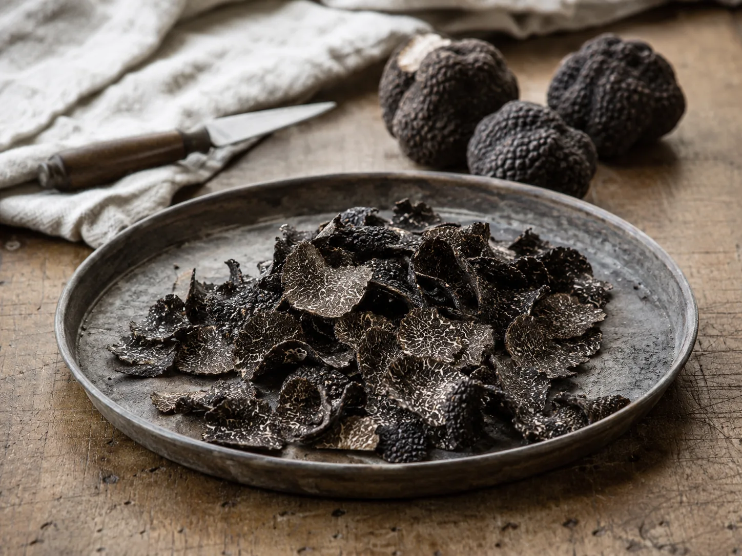 Truffle peelings: black truffle trimmings gathered in a tray after cleaning whole pieces